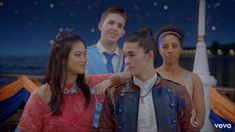 three young people standing next to each other in front of a city skyline at night