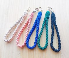 four different colored braided lanyards sitting on top of a wooden table