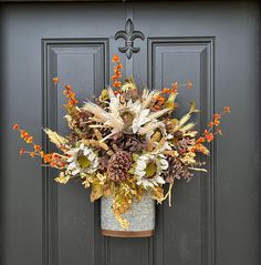 a wreath on the front door of a house decorated with fall foliages and flowers