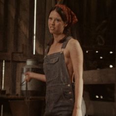 a woman in overalls standing next to a pot