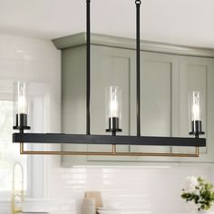 a kitchen light with three lights hanging from it's center island in front of cabinets