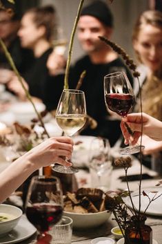 several people sitting at a table with wine glasses in their hands and plates on the table