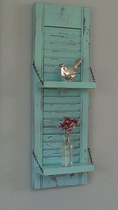 an image of a bird on a shelf with flowers in a vase and another photo