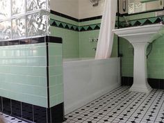 a bathroom with black and white tiles on the floor, green walls and bathtub