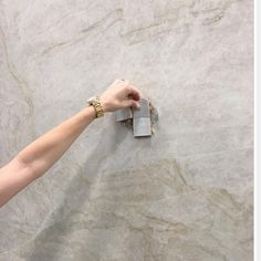 a person's hand is pointing at something on the wall that looks like marble