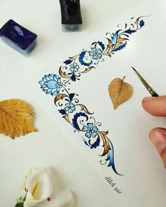 a person is using scissors to cut out leaves on a piece of paper with ink