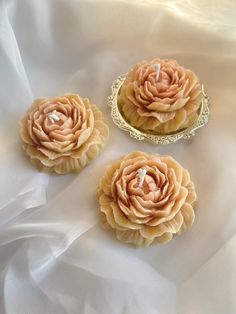 three decorative flowers sitting on top of a white cloth