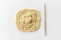 a crochet square with a pencil next to it