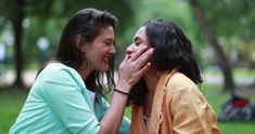 two women sitting on the ground talking and laughing