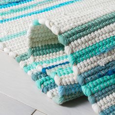 a close up of a rug on the floor with blue and white stripes in it