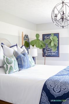 a white bed with blue and green pillows