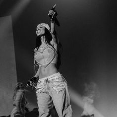 a woman standing on top of a stage with her arms in the air and one hand up