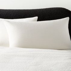 two white pillows sitting on top of a black headboard next to a pillow case