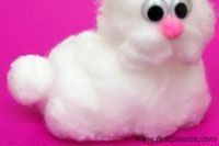 a white stuffed animal sitting on top of a pink surface