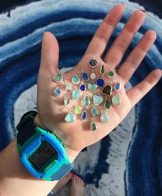 a person's hand with lots of different colored jewels on it and a watch