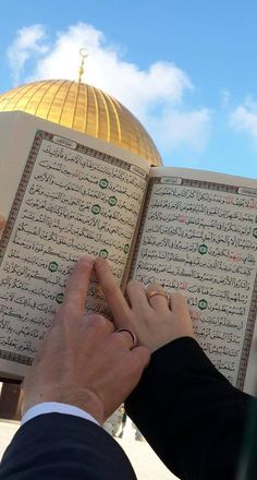 a person holding an open book in front of a dome