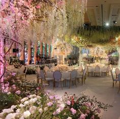 an elaborately decorated banquet hall with flowers and chandeliers hanging from the ceiling