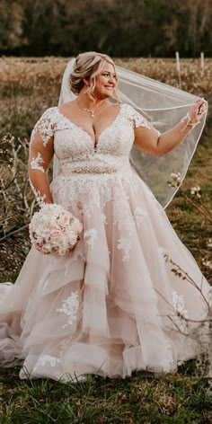 a woman in a wedding dress holding a veil and posing for the camera with her hands on her hips