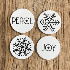 three buttons with the words peace, joy and snowflakes on them sitting on a wooden surface