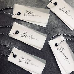 four place cards with name tags attached to them on twine corded ends, sitting on the floor