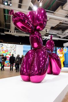 a large purple balloon dog sitting on top of a white platform in front of people