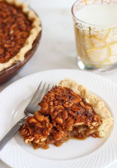 a piece of pecan pie on a plate with a fork and glass of milk