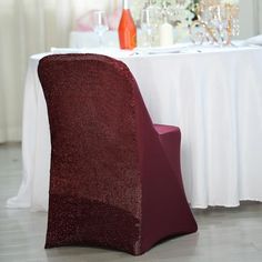 a red chair sitting in front of a table with wine glasses on top of it