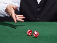 two red dices sitting on top of a green table next to a man in a vest