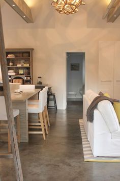 a living room filled with furniture next to a kitchen and dining room table in front of a doorway