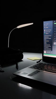 an open laptop computer sitting on top of a desk next to a mouse and lamp