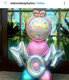 balloons are stacked on top of each other in front of a window with palm trees