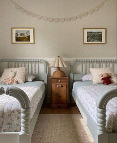 two twin beds in a small room with pictures on the wall and carpeted floor