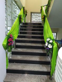 the stairs are decorated with green drapes and flowers