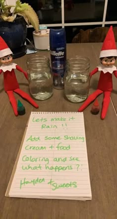 three elfs sitting at a table with some writing on the paper and two jars