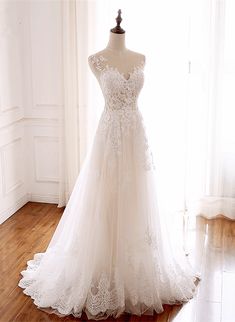 a wedding dress is displayed on a mannequin in front of a white wall