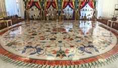 an elaborately designed floor in the middle of a room with red and green curtains