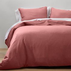 a bed with pink linens and white pillows