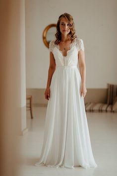 a woman in a white dress is smiling at the camera while standing next to a mirror