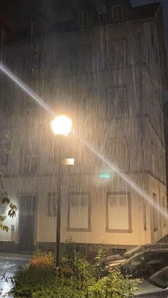 the street light shines brightly on a rainy night in front of an apartment building