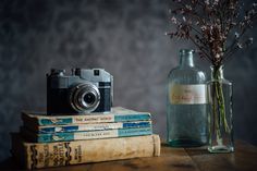 a camera sitting on top of three books next to a bottle