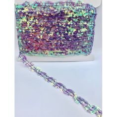 a purple and green sequinized purse on a white box with a silver chain