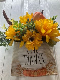 a white vase filled with yellow flowers and pumpkins