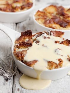 two white bowls filled with food on top of a wooden table