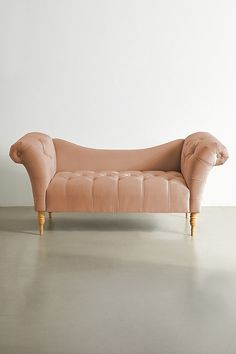 a pink couch sitting on top of a floor next to a white wall in an empty room