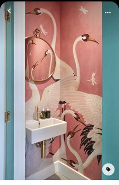 a bathroom with flamingos painted on the wall next to a white sink and mirror