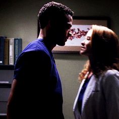 a man and woman standing next to each other in front of a bookshelf