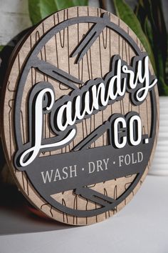 a wooden sign that says laundry co wash dry fold next to a potted plant