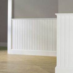 an empty room with white paneling and wood floors