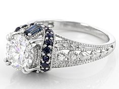 an antique style engagement ring with blue and white stones on the sides, set in 18k white gold