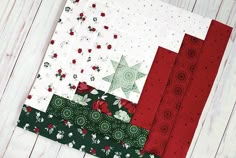 the quilts are all different colors and patterns on the table top, including red, green and white